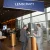 A sleek conference hall in London with navy and gold signage, a speaker on stage, and attendees networking with drinks, captured from a low angle showing the elegant décor.